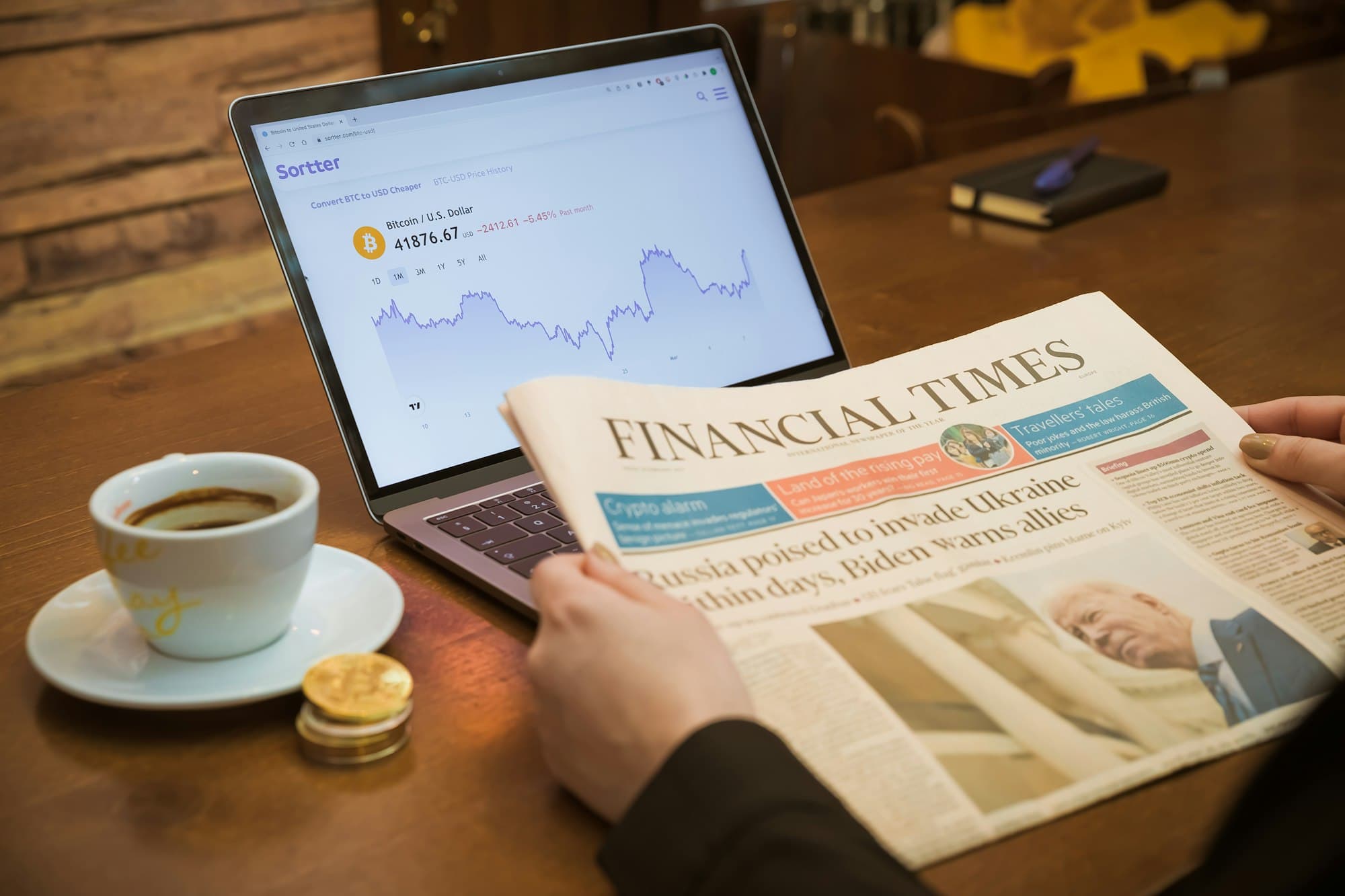 A financial newspaper, a laptop and a coffee on a desk — photograph